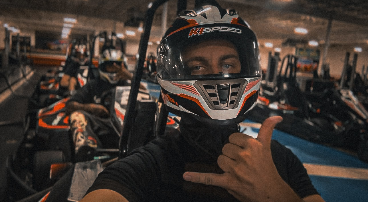 Ben in a racing helmet seated in a go-kart at the track